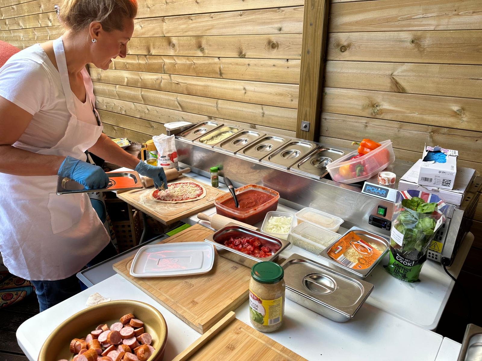 Adding toppings to a fresh pizza at the party